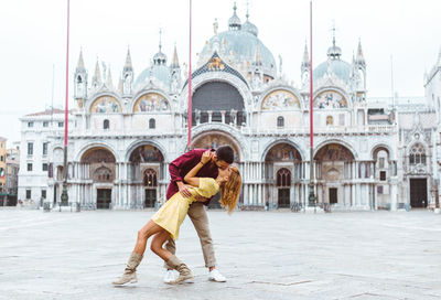 Smiling couple embracing against historic building