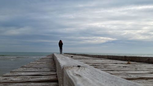 Man standing on pier over sea against sky