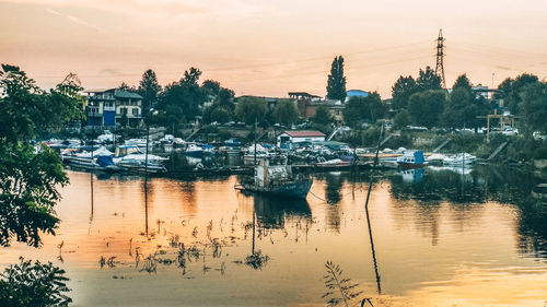 Sailboats moored in lake against sky during sunset