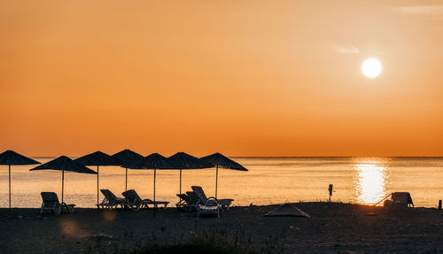 Silhouette people on beach against sky during sunset