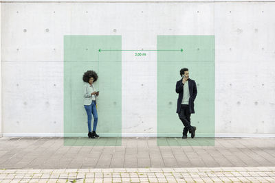 Full length of a young woman standing against wall