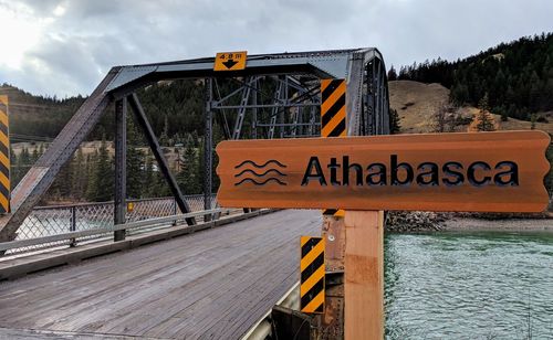 Information sign by bridge against sky