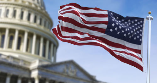 Low angle view of flag against building against sky