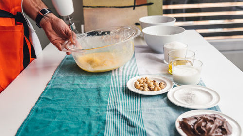 Cropped image of man mixing eggs in bowl at table in kitchen