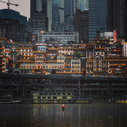 Rear view of man fishing in river against cityscape