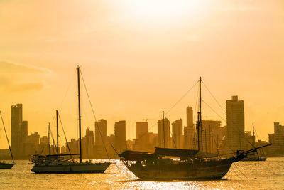 Sailing ships in sea against sky during sunset