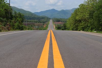 Road by trees against mountain range