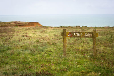 Information sign on field by sea against sky