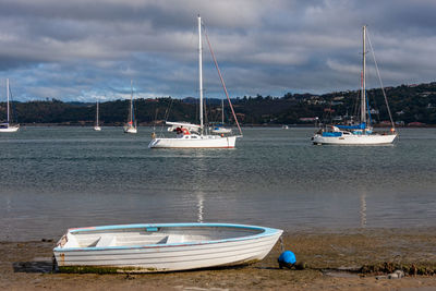 Sailboats moored on sea against sky