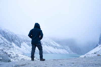 Rear view of man standing on snowcapped mountain