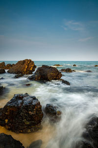 Scenic view of rocks in sea against sky