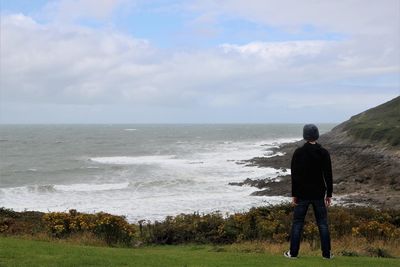 Rear view of man standing on beach against sky