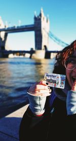 Portrait of man holding drink at river