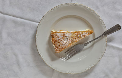A slice of cake on a white plate with a small fork.