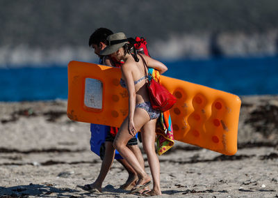 Woman holding umbrella while standing on beach