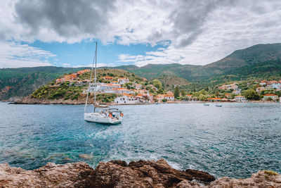 Sailboat sailing on sea by mountains against sky