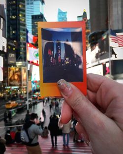 Close-up of hand holding photograph in city