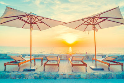 Deck chairs at beach during sunset