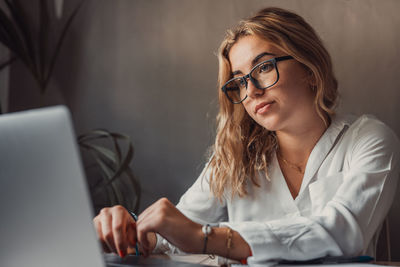 Portrait of young woman using mobile phone while sitting in office