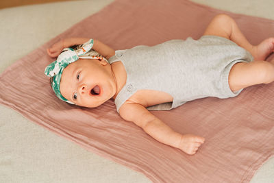 Portrait of cute baby lying on sofa at home