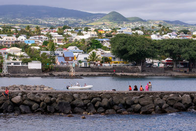 People on town by sea against buildings in city