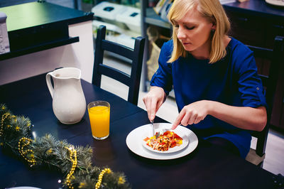 Woman eating food at home during christmas