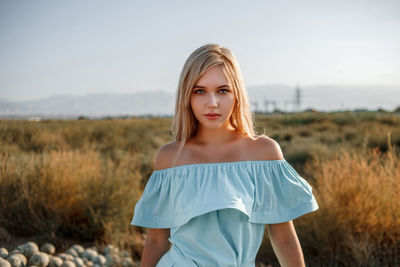 Portrait of teenage girl wearing dress standing on land against sky