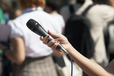 Cropped hand of journalist holding microphone in city