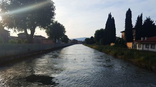 Wet road amidst trees against sky during rainy season