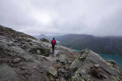 Rear view of man walking on mountain against sky