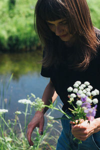 Woman holding flowers standing by lake