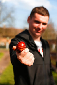 Ukrainian young man holding one colored red egg on nature background. easter, ukraine. craft 