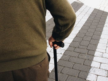 Rear view of man standing with walking cane on street