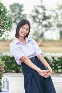 Portrait of young woman standing against trees