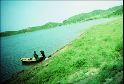 People in boat on shore against sky