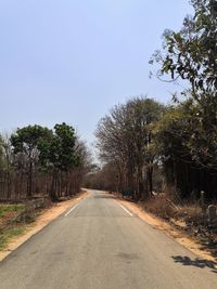 Road amidst trees against clear sky