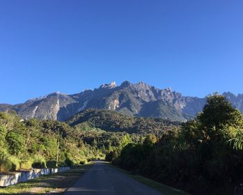 Road amidst mountains against clear blue sky