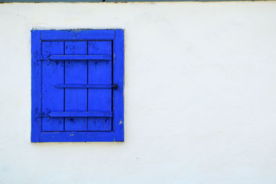 Close-up of blue window on white wall