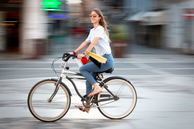 Full length of woman riding bicycle on city