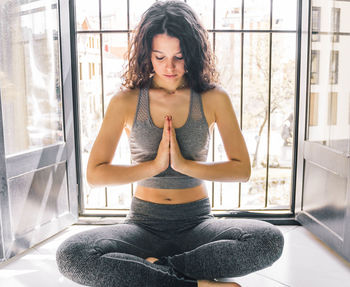 Young girl doing yoga at the window