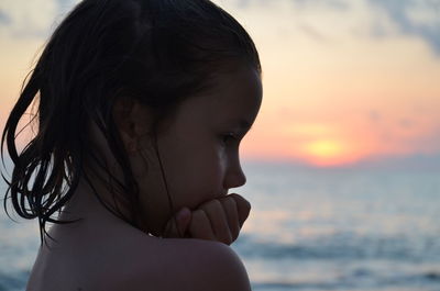 Close-up portrait of woman looking at beach during sunset
