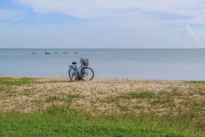 Bicycle by sea against sky