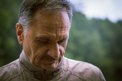 Close-up of senior man standing against trees