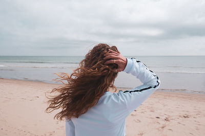 Woman standing at beach against sky