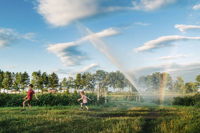 Children running away from a giant sparkler at sunset