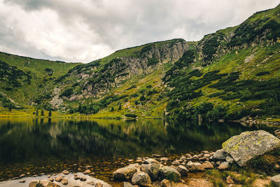 Scenic view of lake by mountains against sky