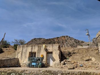 Abandoned building by rocky mountain against sky