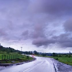 Road amidst field against sky