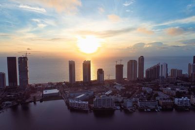 Scenic view of sea and buildings against sky during sunset