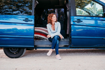 Thoughtful woman sitting in open camper trailer